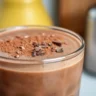 Glass of creamy chocolate smoothie topped with chocolate shavings.