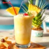 Bahama Mama Tropical Smoothie in a glass with tropical fruit garnish, presented on a wooden table.