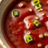 A close-up view of homemade Korean BBQ Sauce in a bowl, served with grilled meat and garnished with sesame seeds and green onions.