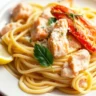 Lobster Pasta served on a white plate with creamy sauce, lobster chunks, herbs, and lemon garnish.