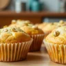 Freshly baked pistachio muffins with visible chopped pistachios on top, showing their fluffy texture and light green color.