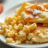 Scrambled pancakes on a white plate with syrup and powdered sugar.