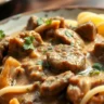 A delicious plate of vegan beef stroganoff featuring plant-based beef slices, creamy sauce, mushrooms, and pasta, garnished with parsley.