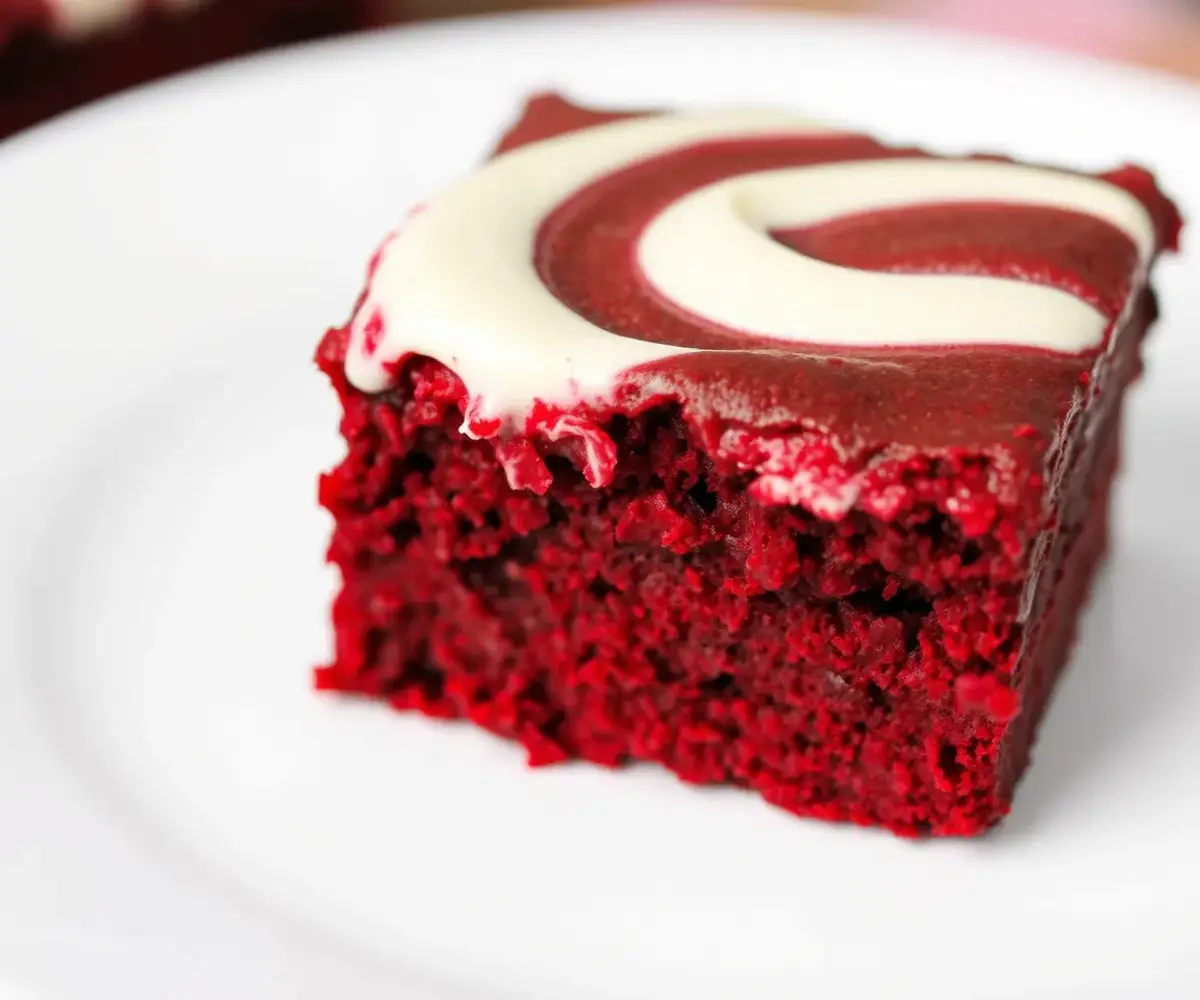 A red velvet brownie with cream cheese frosting on a white plate.