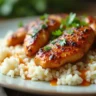 A delicious plate of chicken over rice with tender chicken, fluffy rice, and fresh herbs, presented elegantly.