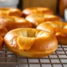 Freshly baked gluten free bagels on a cooling rack with a golden-brown crust and soft, chewy interior.