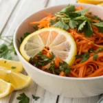 Ensalada de zanahoria receta casera en un tazón blanco, con zanahorias ralladas, aderezo cremoso y perejil fresco como decoración