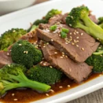 Plato de ternera con brócoli estilo chino con tiras de carne jugosa y brócoli verde brillante en salsa oscura servido en plato blanco