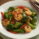 Salteado de camarones con brócoli fresco en plato blanco, receta rica en proteínas