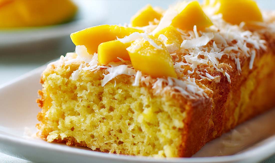 Ein detailreiches Food-Foto zeigt den Mango-Kastenkuchen mit Kokos – einen exotischen, saftigen Kastenkuchen mit frischen Mangostücken und gerösteten Kokosraspeln. Perfekt für den Sommer und ideal als süßes Dessert oder Kaffeekuchen.