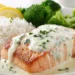 Creamy garlic salmon with rice and broccoli served on white plate with golden seared crust and ivory cream sauce