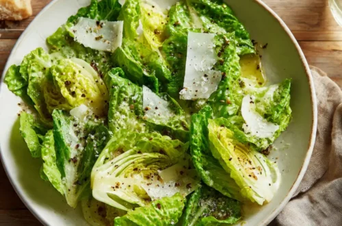 Simple green salad with fresh lettuce, olive oil dressing, and shaved Parmesan cheese in a white bowl