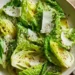 Simple green salad with fresh lettuce, olive oil dressing, and shaved Parmesan cheese in a white bowl