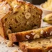 Sliced Hawaiian banana bread loaf on wooden cutting board showing moist golden interior with coconut flakes and macadamia nuts
