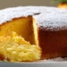 Fluffy yogurt and orange pudding cake dusted with powdered sugar on a white cake stand